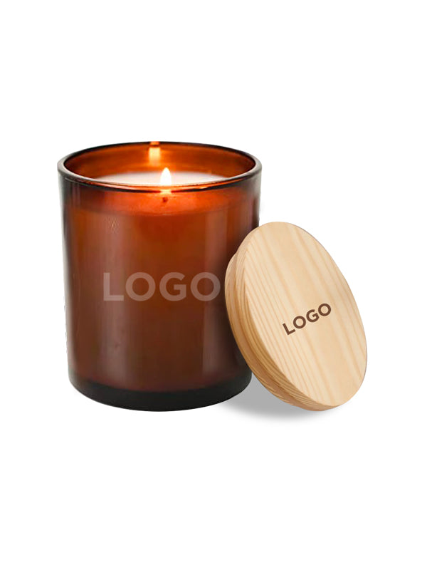 An amber glass jar candle with a lit flame, shown next to a light natural wood lid engraved with the word 'LOGO'.