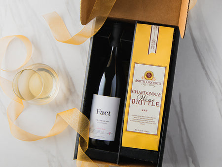 Wine bottle in a gift box with a yellow ribbon on a light background