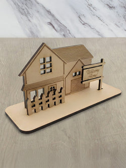 Model house card with a 'Welcome Home' sign on a marble surface
