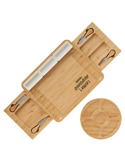 A bamboo charcuterie board set with multiple compartments, three white cheese inserts, four small knives with dark handles, and a round matching bamboo lid, shown on a plain white background.