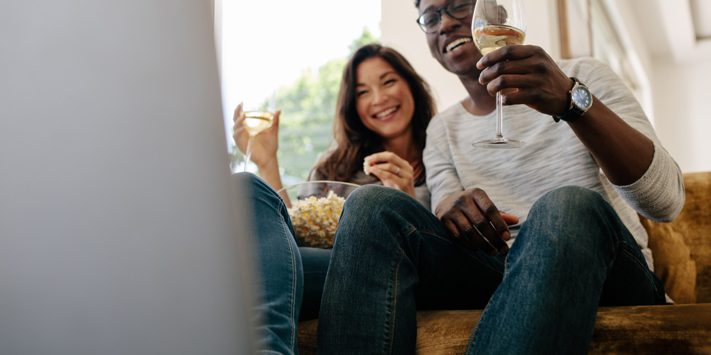 Couple enjoying wine and popcorn while watching movie