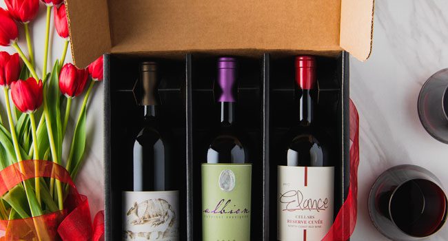 3 bottles of red wine in gift box with red flowers and red wine glasses