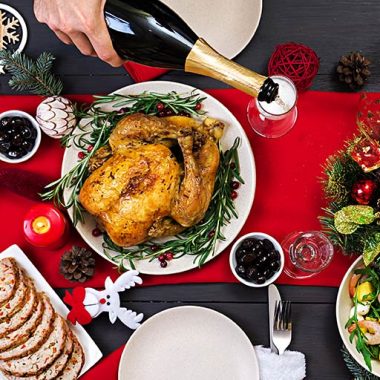 Holiday table with food and person pouring sparkling wine