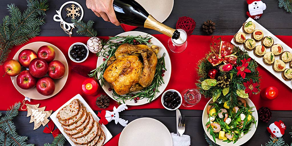 Holiday table with food and person pouring sparkling wine