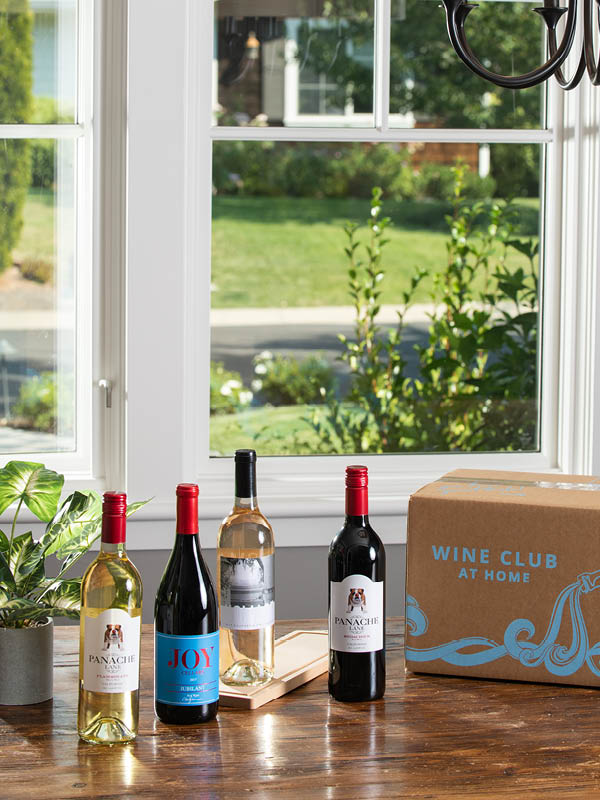 2 red and 2 whites WineShop At Home artisan wines for Wine Club Membership displayed on kitchen table with the Wine Club box.