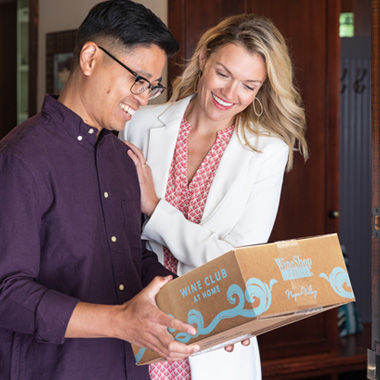 Man and woman receiving wine club box at their door