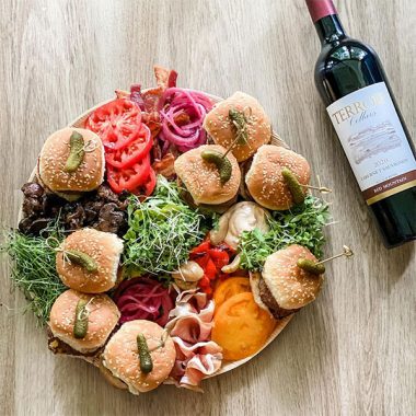 A bottle of Terroir Cellars 2020 Cabernet Sauvignon next to platter of sliders with various topings