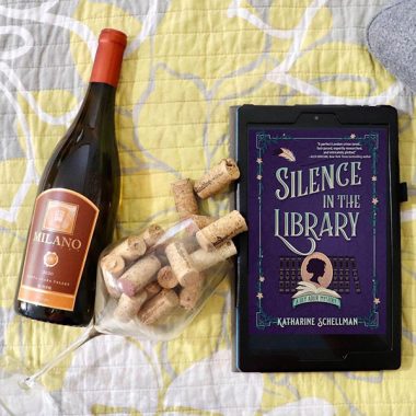 A bottle of Milano Cellars 2020 Trilogy next to a wine glass filled with corks and a digital copy of "Silence in the Library"