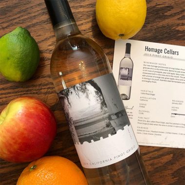 A bottle of Homage Cellars 2019 Pinot Grigio next to its VintNote and various fruits
