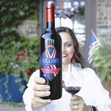 Consultant holding a bottle and filled glass of Glory Cellars 2017 Hero's Blend