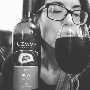 A close up of a Consultant enjoying a full glass and bottle of Gemme Cellars 2014 Ruby