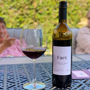 A bottle of Fact Cabernet Franc and filled glass on an outdoor patio table