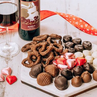 A bottle of Ceres Goddess next to a wine glass paired iwth an assortment of chocolate covered treats